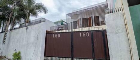 A gated residential area with a concrete wall and a metal gate marked with the number 168.