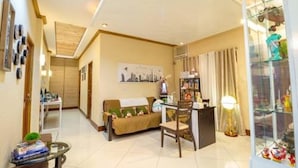 A living room with a sofa, a coffee table, a dining table with chairs, a glass cabinet with toys, and a wall-mounted picture. - U Feel Home (Cebu City)
