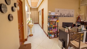A hallway with a reception desk, a bookshelf, and a wall with framed pictures. - U Feel Home (Cebu City)