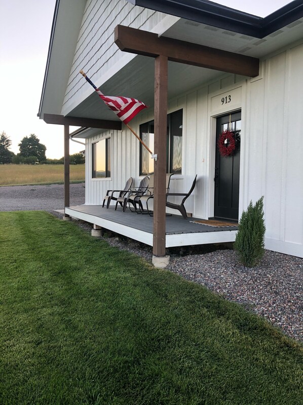 Et hus med veranda, flag og krans ved døren.