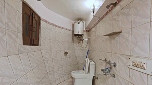 Une salle de bain équipée de toilettes, d’une douche et d’un chauffe-eau.