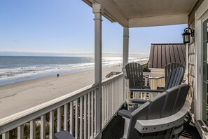 A balcony with a view of the beach and ocean. There are chairs and a table on the balcony. - Beachside in Surfside! (Surfside Beach)