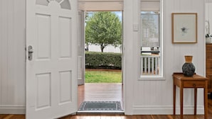 A white door leading to a wooden deck with a view of a tree and a white fence. - The Keeper's House (East Toowoomba)