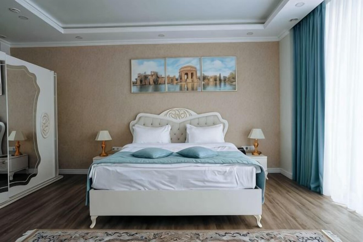 Un dormitorio con una cama, dos mesitas de noche, un espejo y un cuadro en la pared.