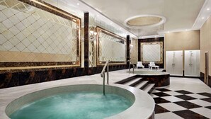 A luxurious bathroom with a large oval bathtub, marble walls, and a checkered floor. - Ramada by Wyndham Shymkent (Shymkent)