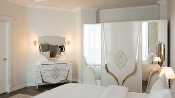 A bedroom with a large bed, a dresser with drawers, a mirror, and a wardrobe.