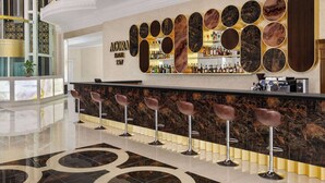 Eine Bar mit einer Marmor-Theke, Barhocker und einer Wand mit runden Dekorationselementen.