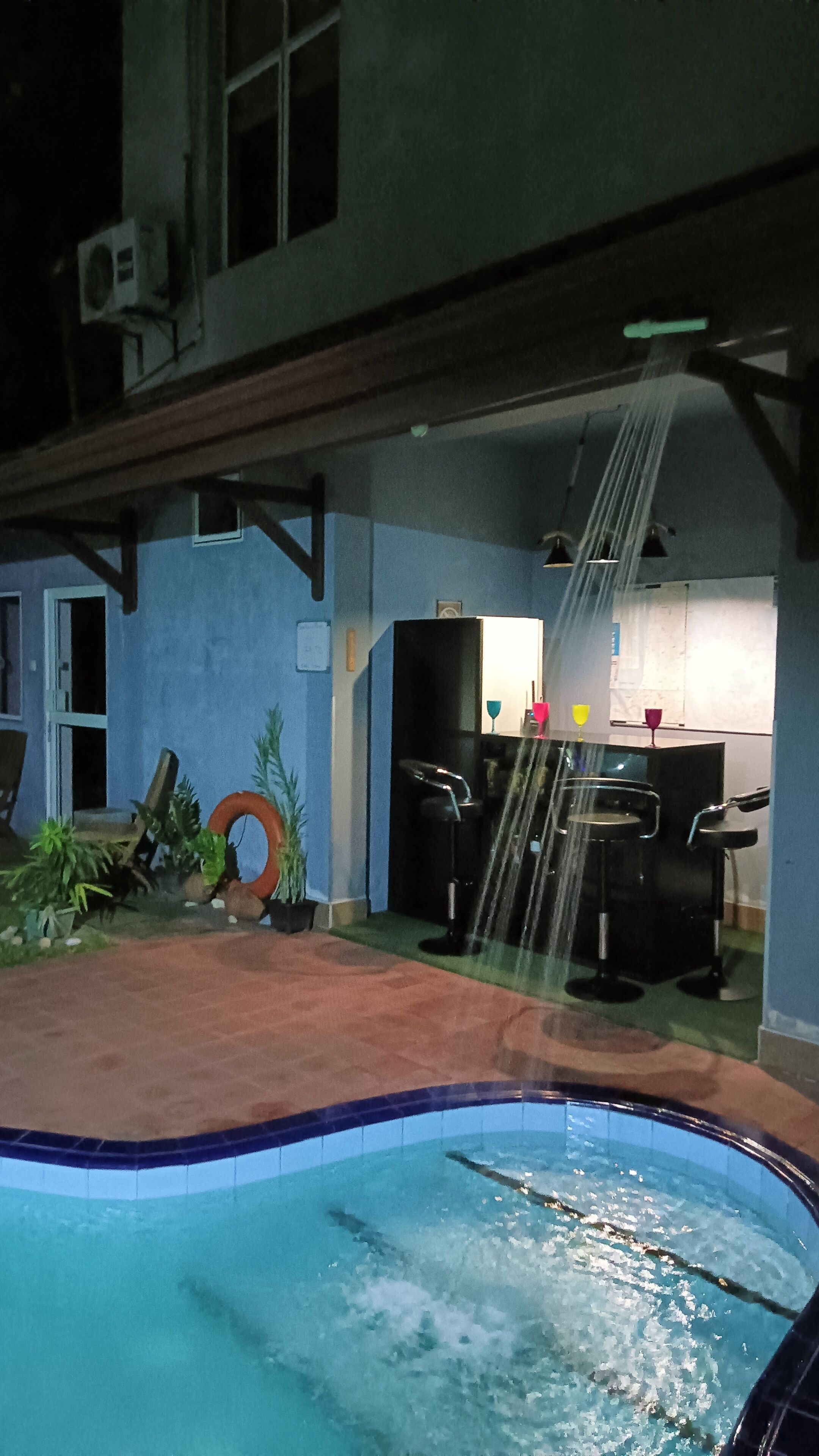 Zona de piscina con jacuzzi, asientos al aire libre y bar.