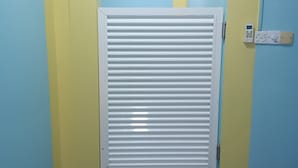 Um corredor com uma porta branca, um termostato e um tapete azul.