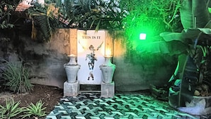 Um caminho leva a uma entrada decorativa com dois vasos e uma placa que diz 'THIS IS IT'.