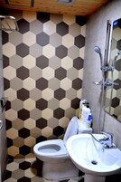 Un baño con un diseño de baldosas hexagonales, un inodoro, un lavamanos y una ducha.