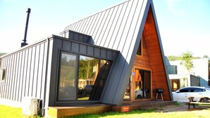 A modern house with a sloped roof, large windows, and a visible chimney.