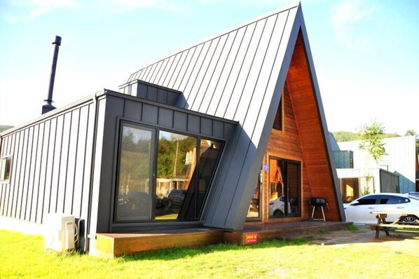 A modern house with a sloped roof, large windows, and a visible chimney.