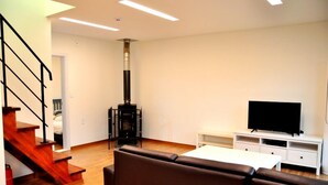 A modern living room with a fireplace, a television on a stand, and a sofa.