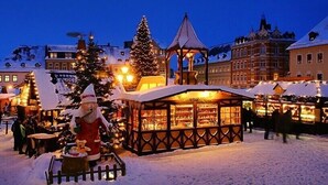 Un mercado al aire libre cubierto de nieve, con un árbol de Navidad y una figura de Papá Noel.