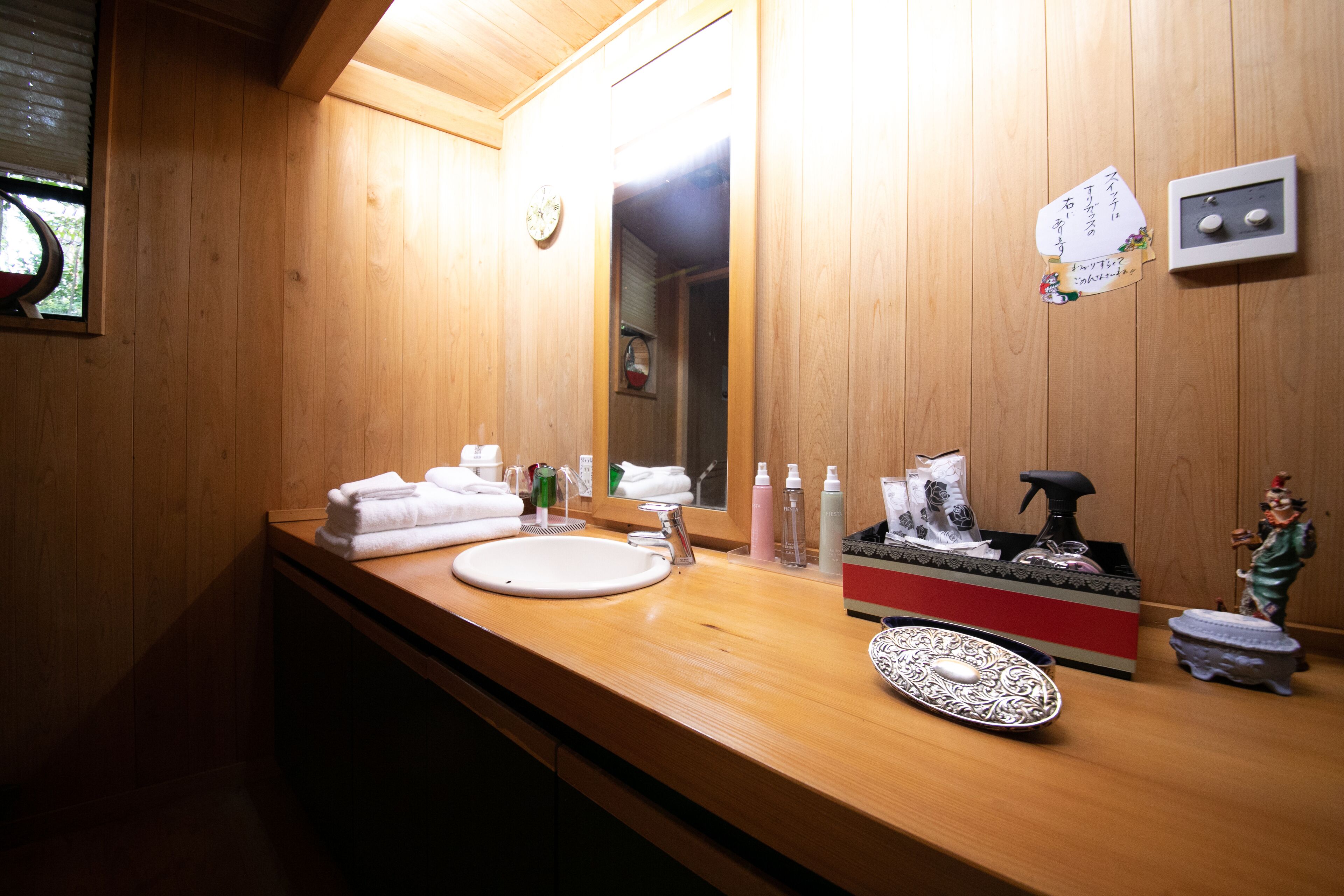 Un baño de madera con un lavabo, espejo y varios artículos de tocador.