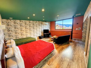 Una habitación con cama, escritorio, silla, televisor y ventana con vistas.