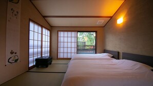 A traditional Japanese-style room with tatami flooring, a futon bed, sliding shoji doors, and a view of the outdoors.