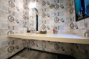 Un baño con tocador, espejo y pared decorativa con un diseño de notas musicales y la frase "Made with love".