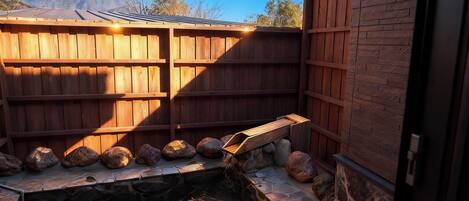 A wooden fence, a stone water feature, and a mountain in the background.