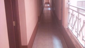 A long, narrow hallway with a tiled floor and a wooden door on the left. - 3 Shades Annex - Adults Only (Thika)