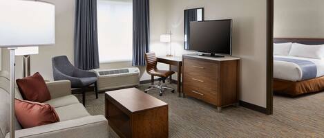 A hotel room with a bed, a desk, a chair, a television, and a lamp.