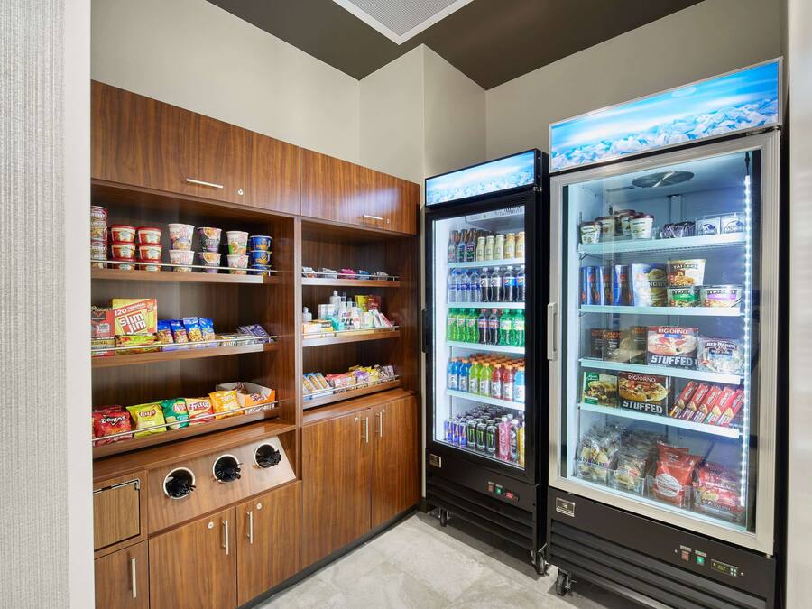 Zona de máquinas expendedoras con aperitivos, bebidas y productos refrigerados.