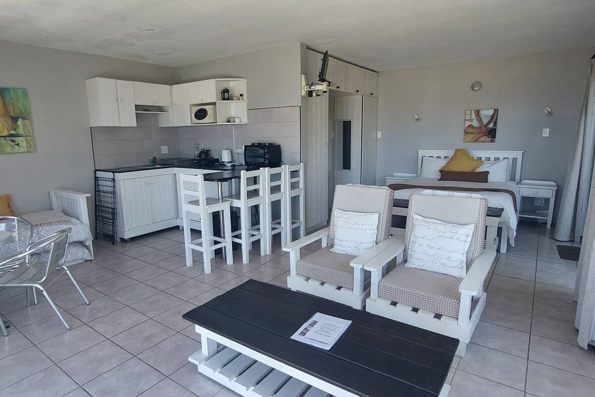 A compact living space with a kitchenette, dining area, and a bed.