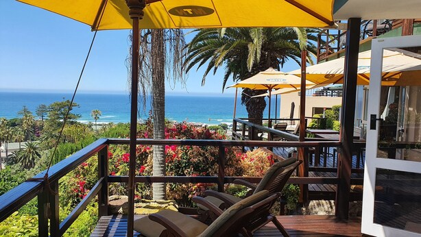 A balcony with a view of the ocean, furnished with lounge chairs and umbrellas. - The Tops (Wilderness)