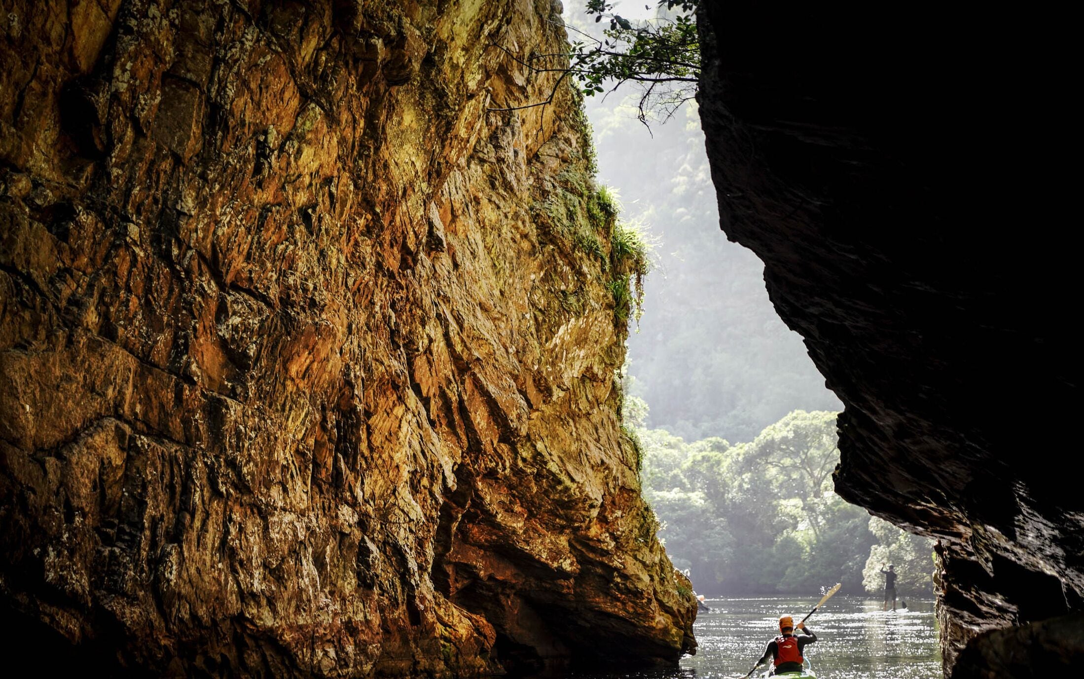 Formación rocosa natural con una persona haciendo kayak en el agua.