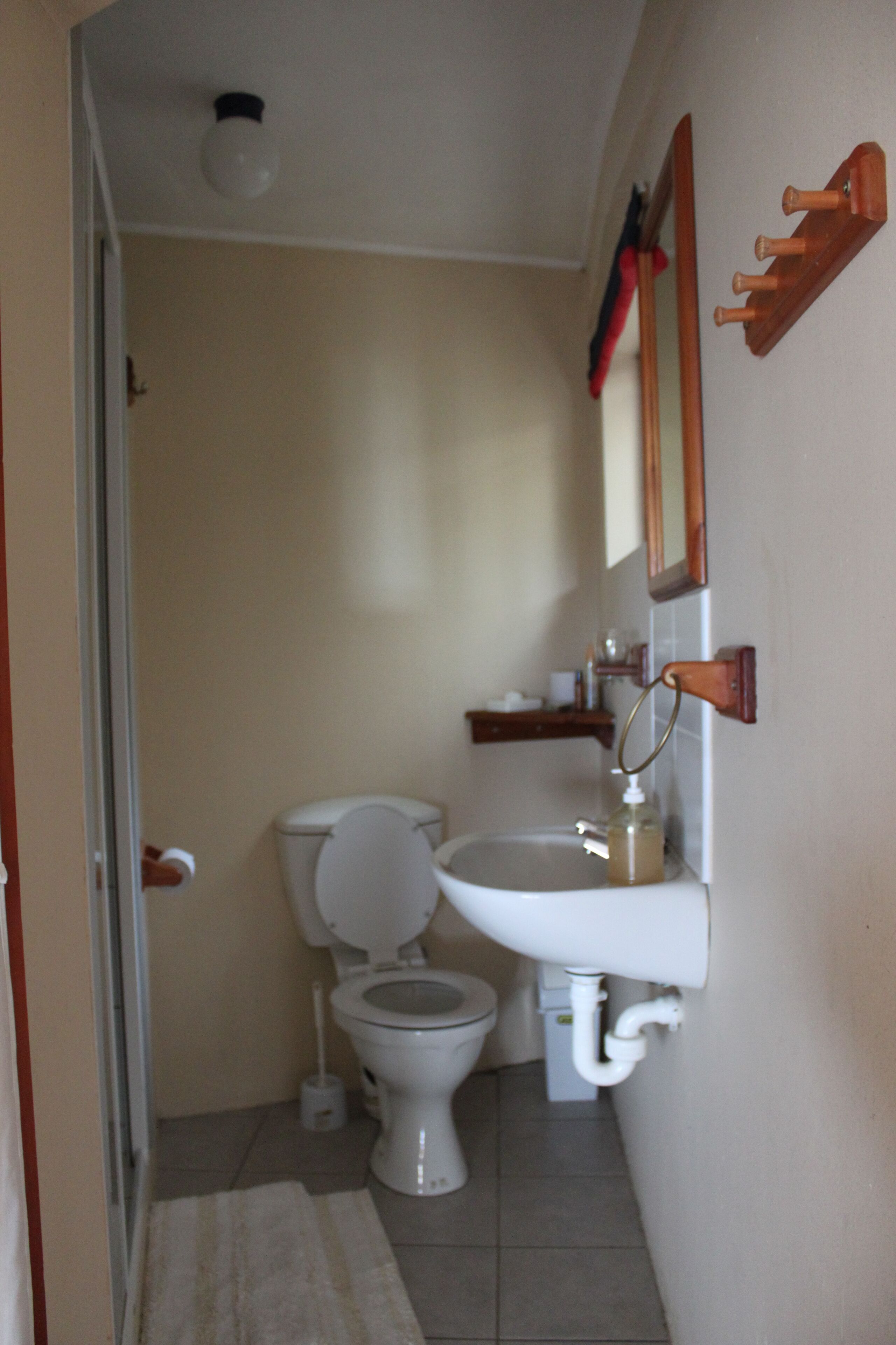 Un baño pequeño con inodoro, lavamanos y espejo.