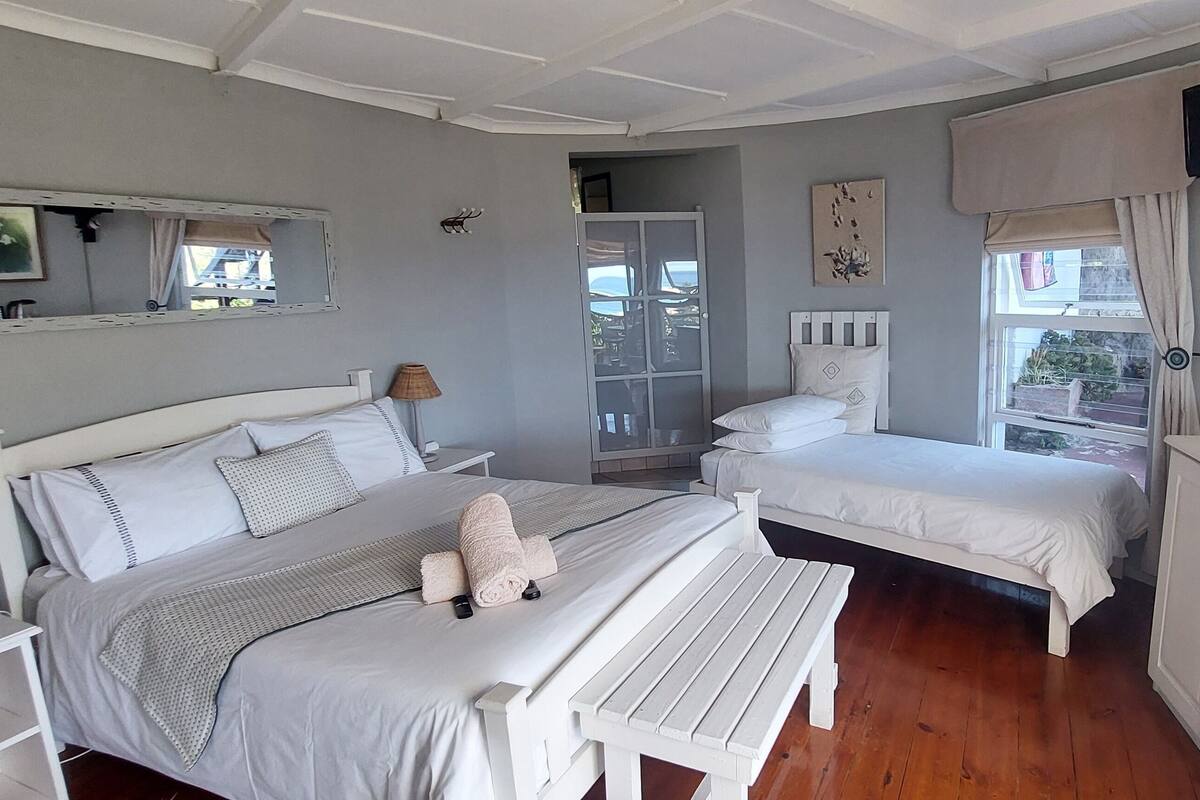 A bedroom with two beds, a small table, a cabinet, and a television on the wall.
