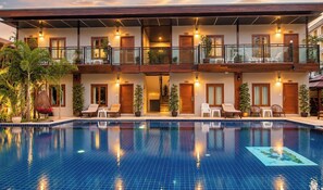 A hotel with a swimming pool, multiple balconies, and outdoor seating areas.