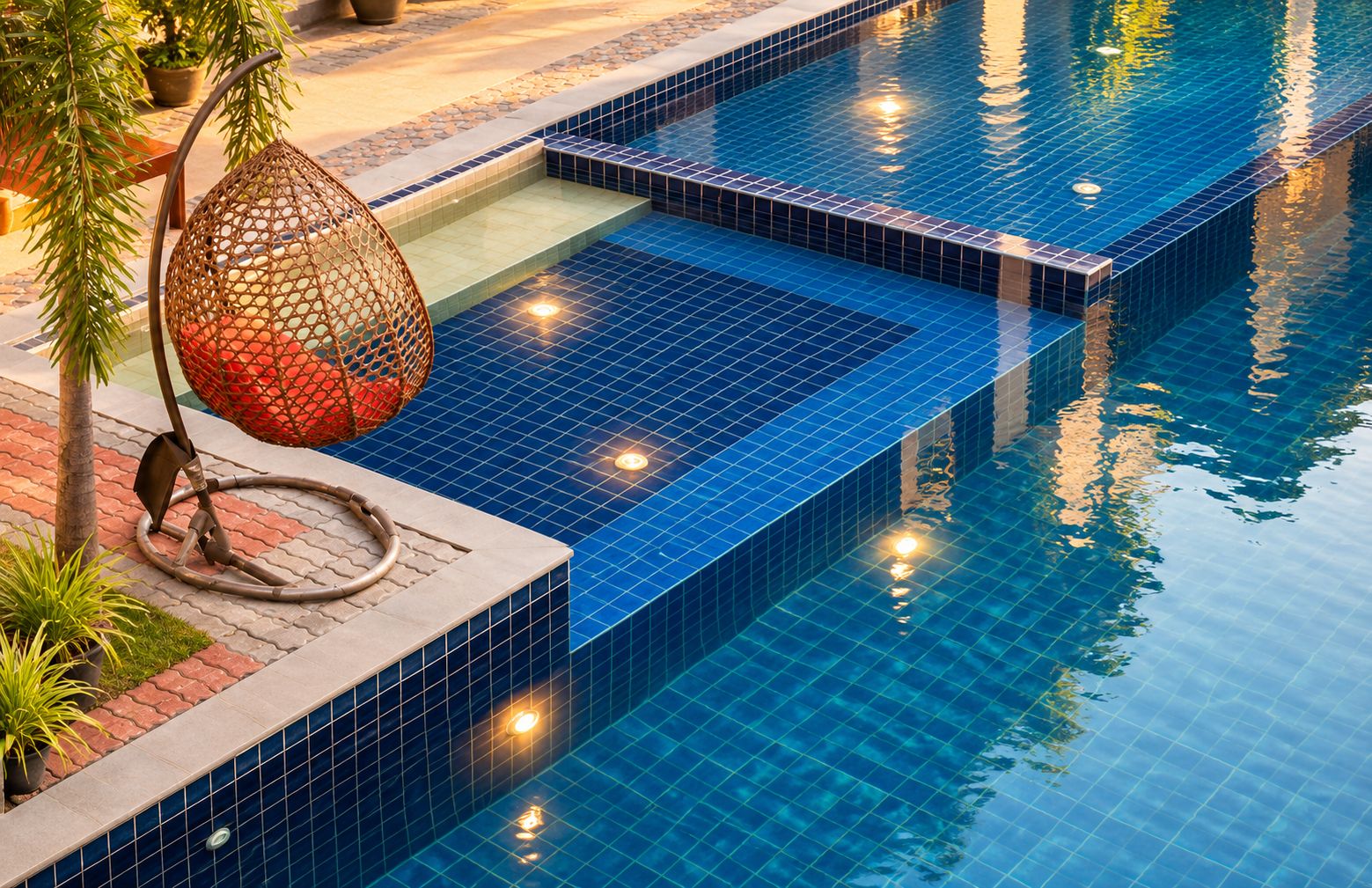 Piscina com azulejos azuis cristalinos, balanço de corda e plantas em vasos.