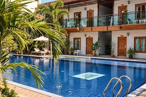 A swimming pool with a clear blue tile design, surrounded by lounge chairs and potted plants. - Paradise Land Resort (Pattaya)