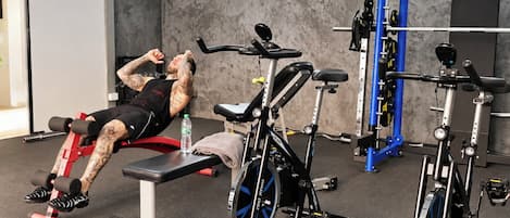 A gym with exercise equipment, a bench, and a water bottle on the floor.