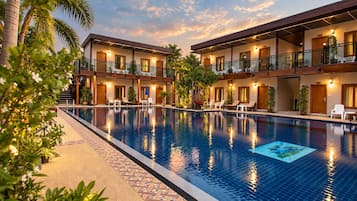 Un hotel con piscina, varios balcones y zonas de estar al aire libre.
