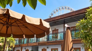 Ein Hotel mit Balkon, Sonnenschirmen draußen und einem Riesenrad im Hintergrund.
