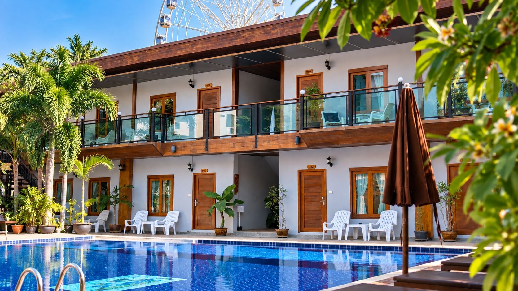 A hotel with a swimming pool, multiple balconies, and outdoor seating.
