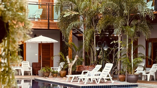 Un área de piscina con sillones de descanso y plantas en macetas.