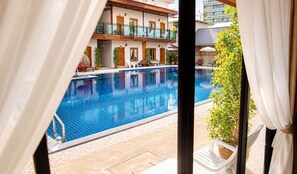 A hotel pool area with a clear view of the pool, lounge chairs, and a building with balconies. - Paradise Land Resort (Pattaya)