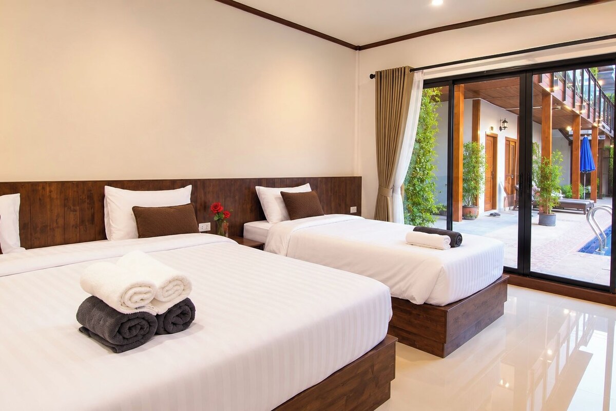 A hotel room with two beds, a large window, and a view of an outdoor swimming pool.