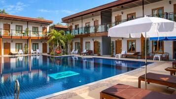 Un hotel con piscina, asientos exteriores y una silla colgante.
