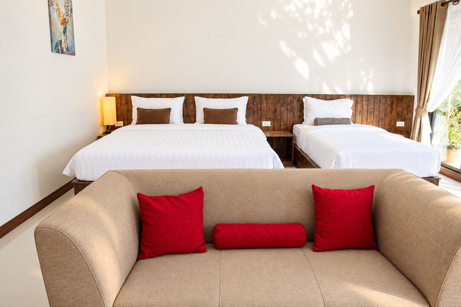 Une chambre d’hôtel avec deux lits, un canapé et un tableau au mur.