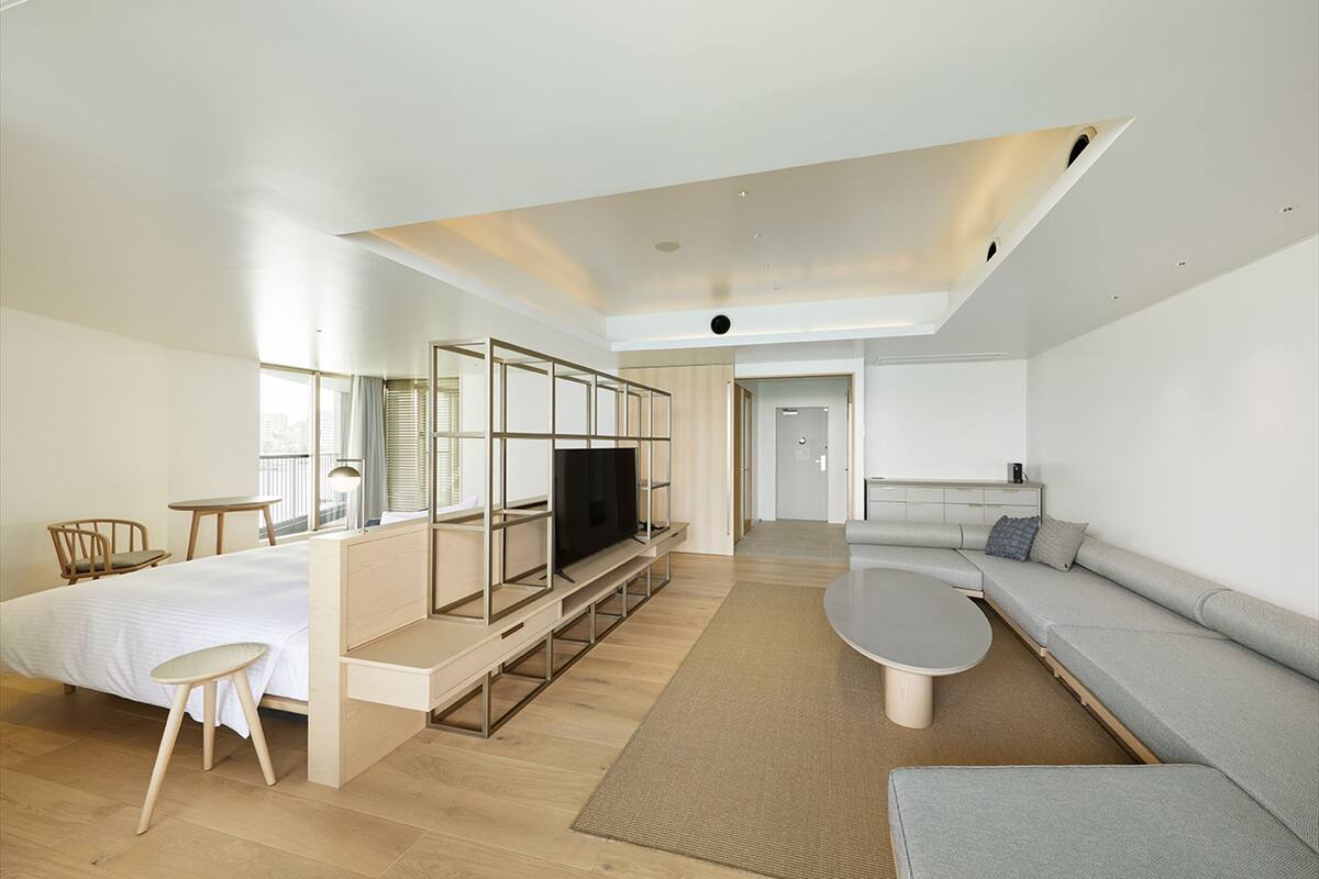 A modern living room with a sofa, a coffee table, a TV, and a dining area with a table and chairs.
