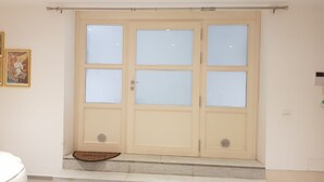 Een set beige dubbele deuren met geëtste glaspanelen, een klein opstapje naar de ingang en een welkomstmat.