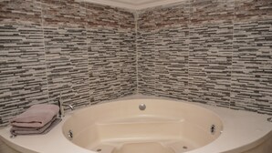 A corner bathroom with a freestanding bathtub, a towel rack, and a tiled backsplash.