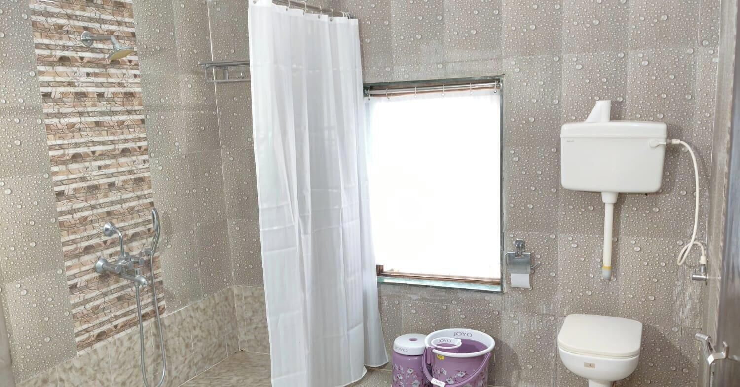 Un baño con ducha, inodoro y ventana.
