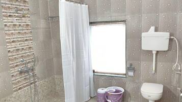 Un baño con ducha, inodoro y ventana.