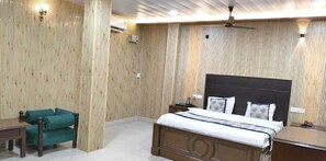 Une chambre avec un mur recouvert de panneaux de bois, un lit doté d’une tête de lit sombre, un fauteuil vert, une table de chevet et une commode.